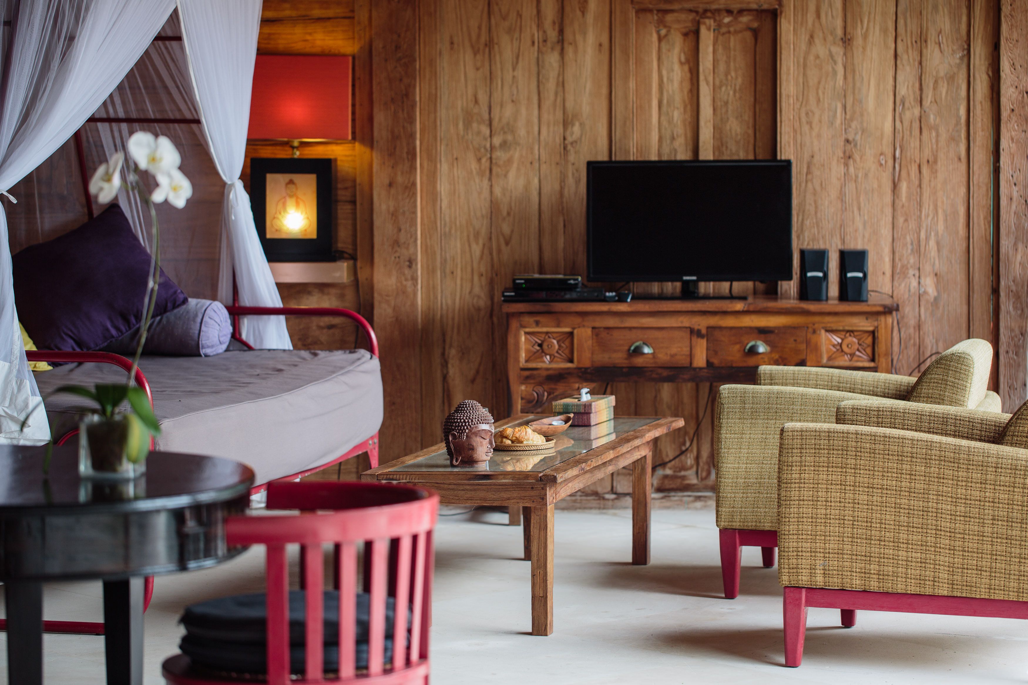 Een kamer met een bed, een televisie, een houten kast, een tafel en een stoel.