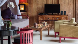 A room with a bed, a television, a wooden cabinet, a table, and a chair. - Villa Madah (Kerobokan)
