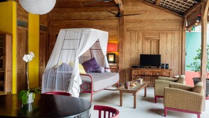 A cozy room with a bed, a television, a dining table, and two chairs. - Villa Madah (Kerobokan)