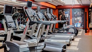 Une salle de sport équipée de plusieurs tapis de course, chacun doté d’un écran numérique et arborant la marque « Life Fitness ».