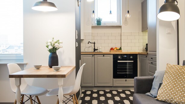 Een moderne keuken met witte kastjes, een zwarte oven en een raam boven de spoelbak.