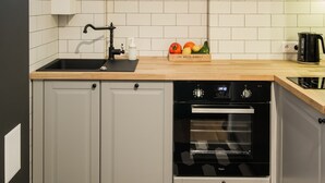Een moderne keuken met witte kasten, een zwarte spoelbak, een raam boven de spoelbak en een ingebouwde oven.