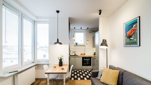 Een moderne keuken met witte kasten, een zwart-wit betegelde vloer en een eethoek met een tafel en stoelen.