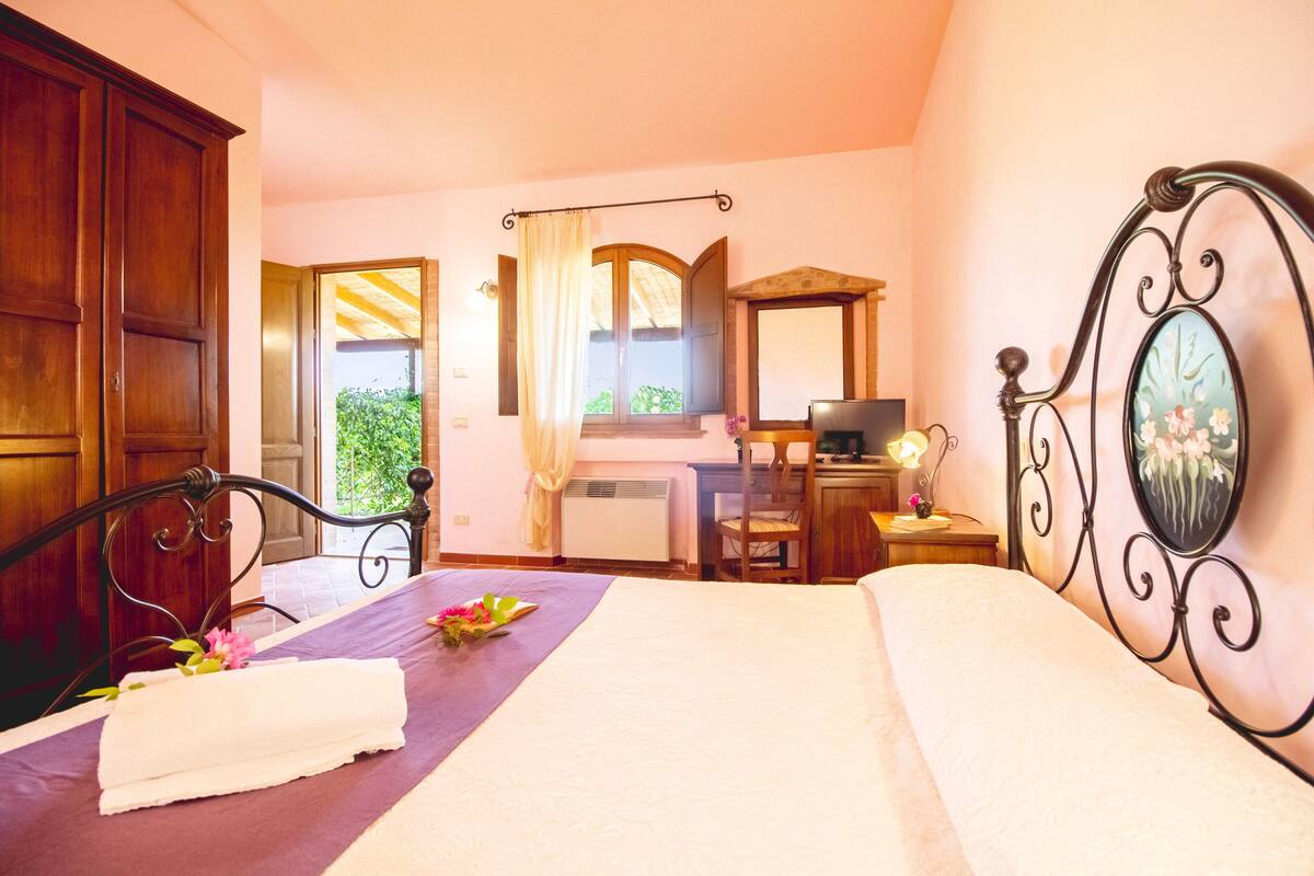 Une chambre à coucher avec un lit, un bureau, une chaise, un téléviseur et une fenêtre avec des rideaux.