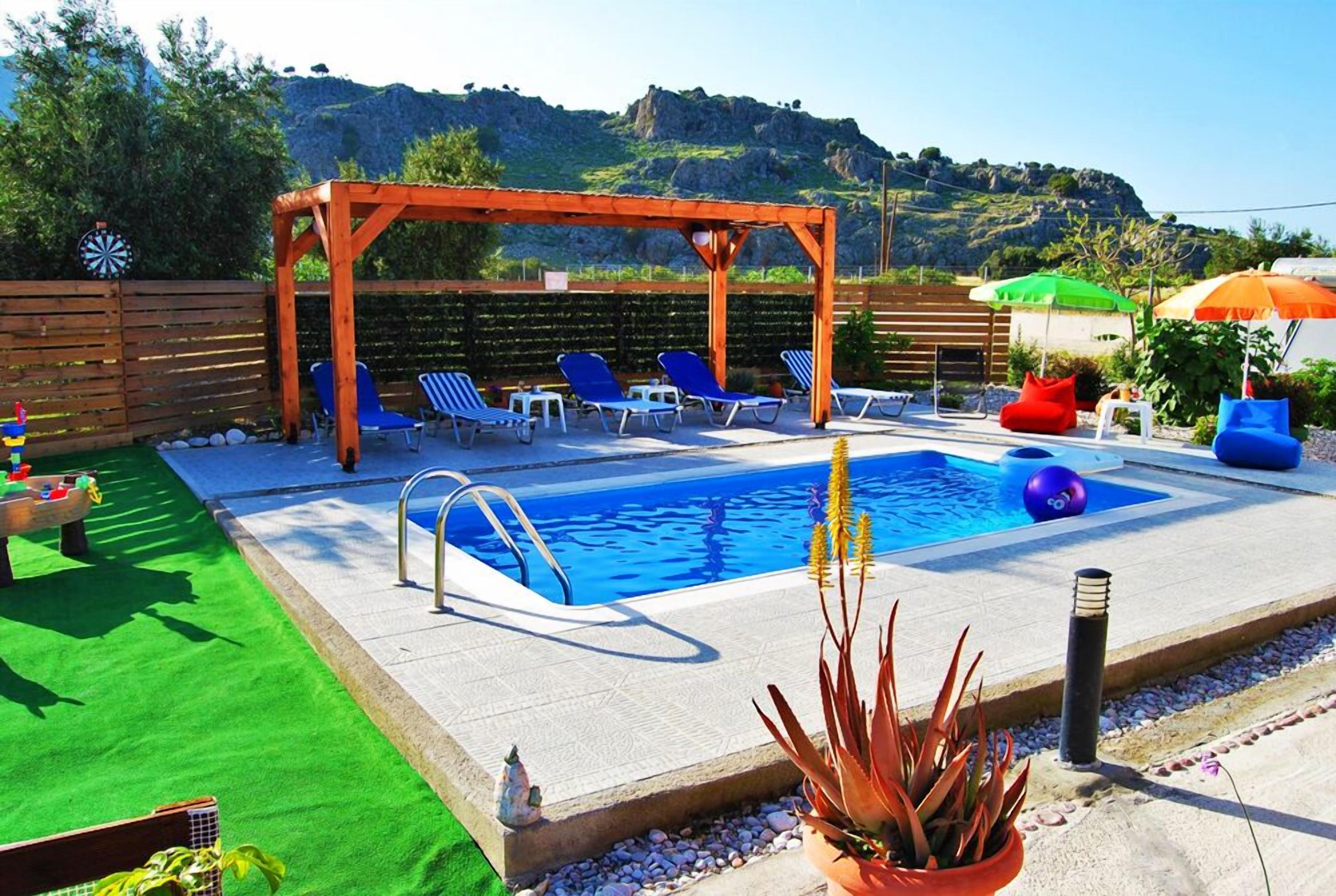 Un espace piscine agrémenté d’une pergola en bois, de chaises longues et d’une petite piscine.