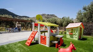 A children's play area with a slide, climbing structure, and a small house. - Stergios Villa (Rhodes)