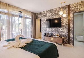 Habitación de hotel con una cama grande, un televisor de pantalla plana en la pared, un minibar y vistas al exterior por la ventana.