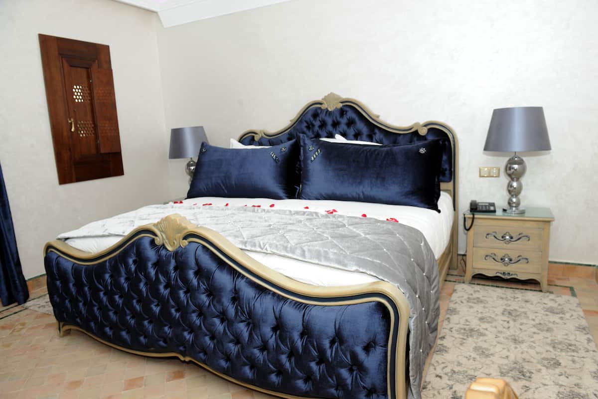 Une chambre à coucher avec un grand lit, une table de chevet, une lampe et une porte.