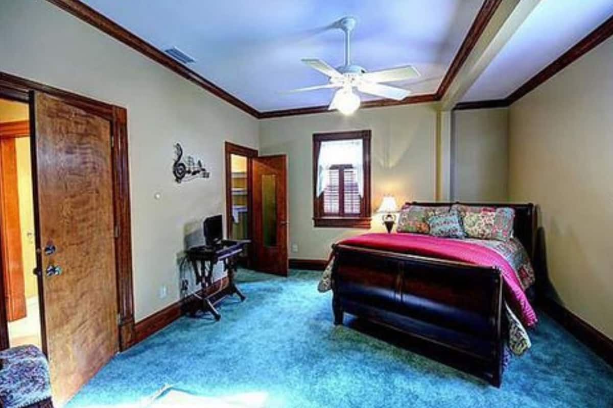 Un dormitorio con cama, escritorio, silla y ventilador de techo.