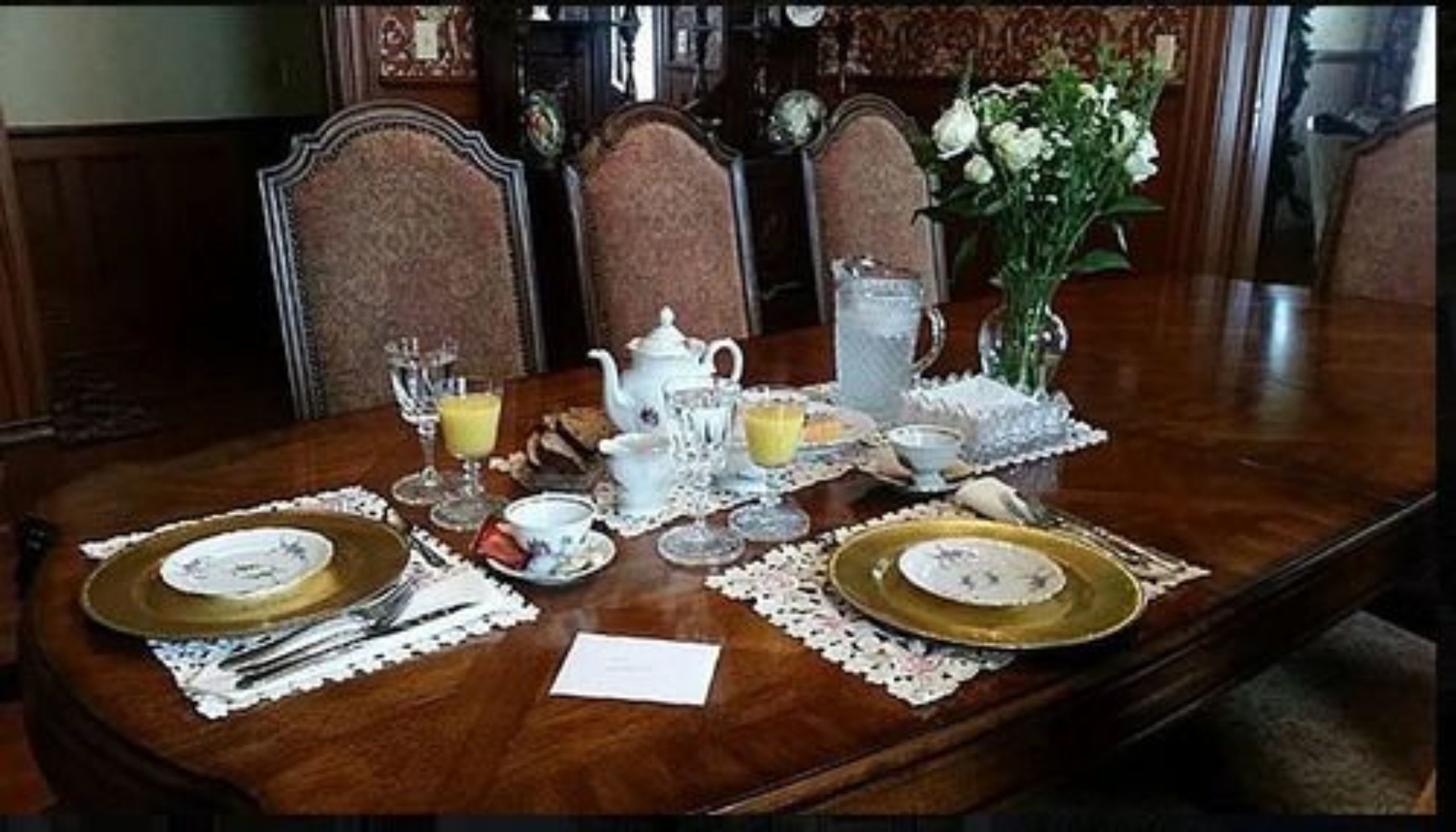 A formal dining table set with fine china, silverware, and a floral centerpiece.