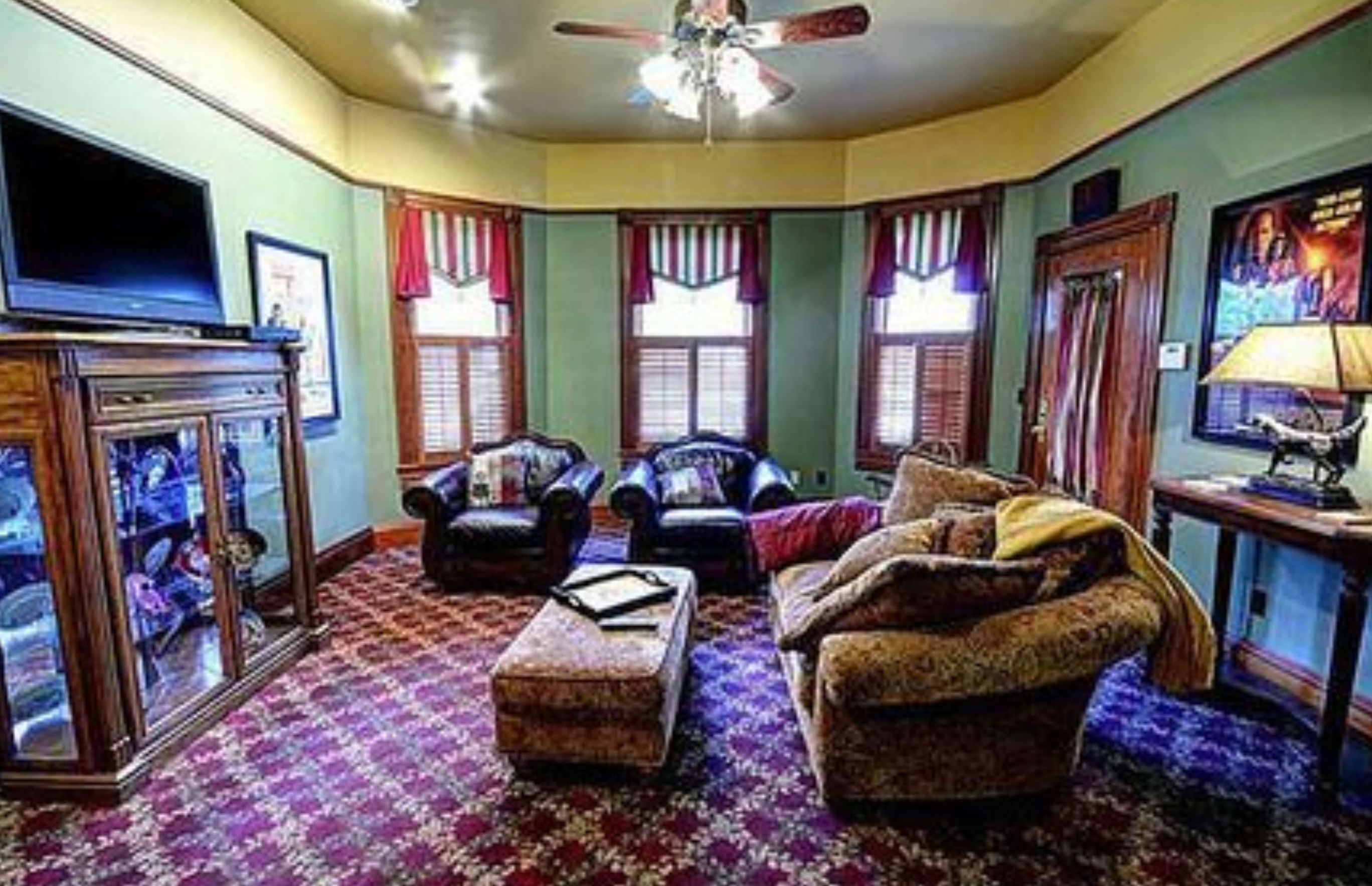 A living room with a television, a ceiling fan, and a fireplace.
