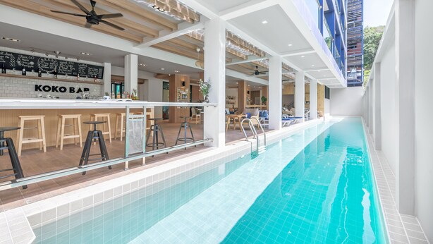 En indendørs swimmingpool med et barområde kaldet 'KOKO BAR' og en loftsvift.