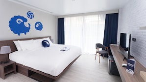 Et moderne hotelværelse med en stor seng, et skrivebord med computer, fjernsyn og minibar.