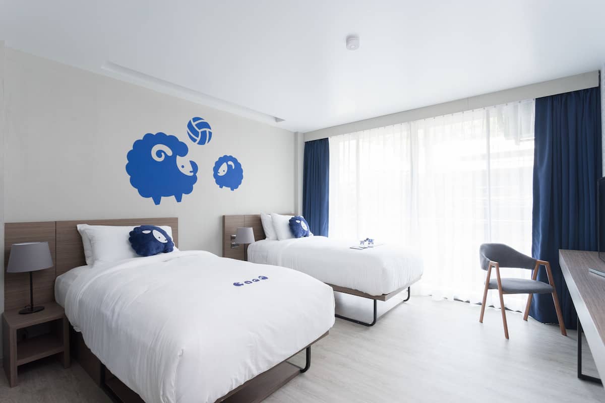 Una habitación de hotel con dos camas, un escritorio y una silla.