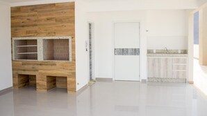 Una cuina moderna amb una illa integrada, parets blanques i una paret decorativa de fusta.