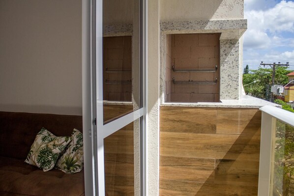 A balcony with a wooden floor, a metal railing, and a door leading to an outdoor area.