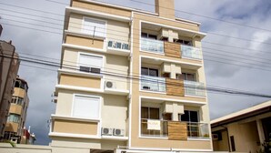 Un edifici d'alguns pisos amb balcons, aires condicionats i una xemeneia.