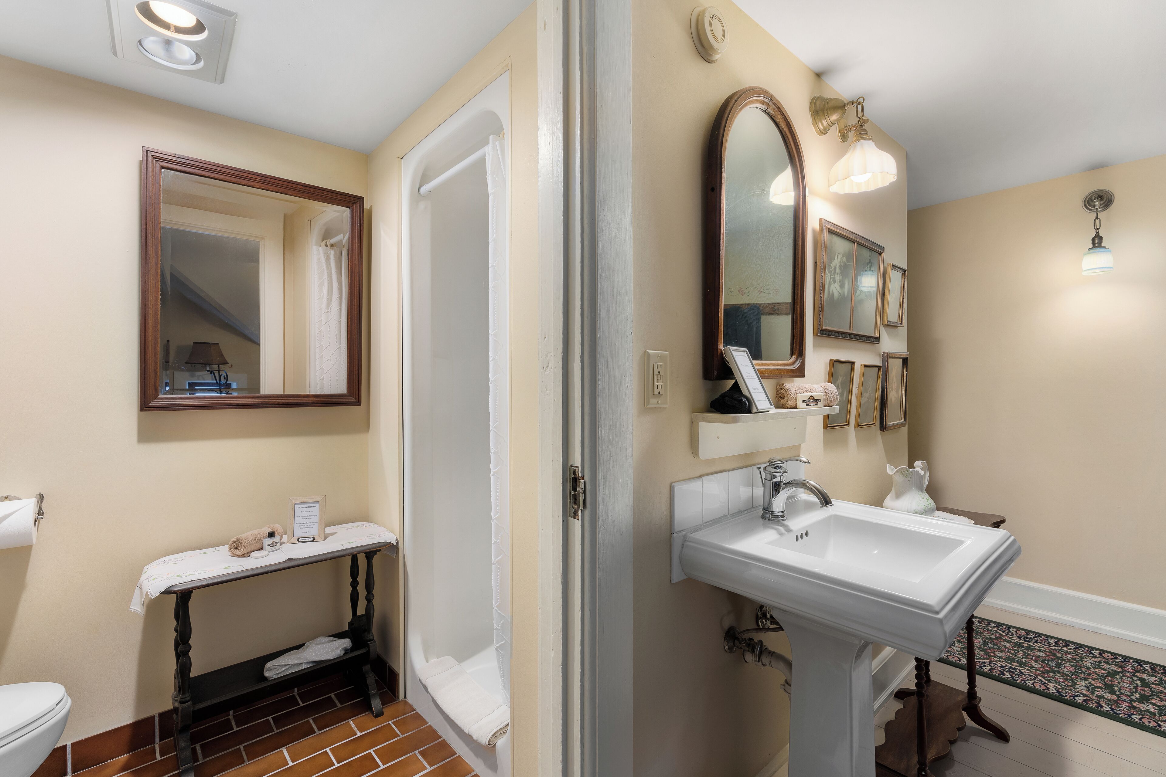 A bathroom with a toilet, a sink, a mirror, and a shower.
