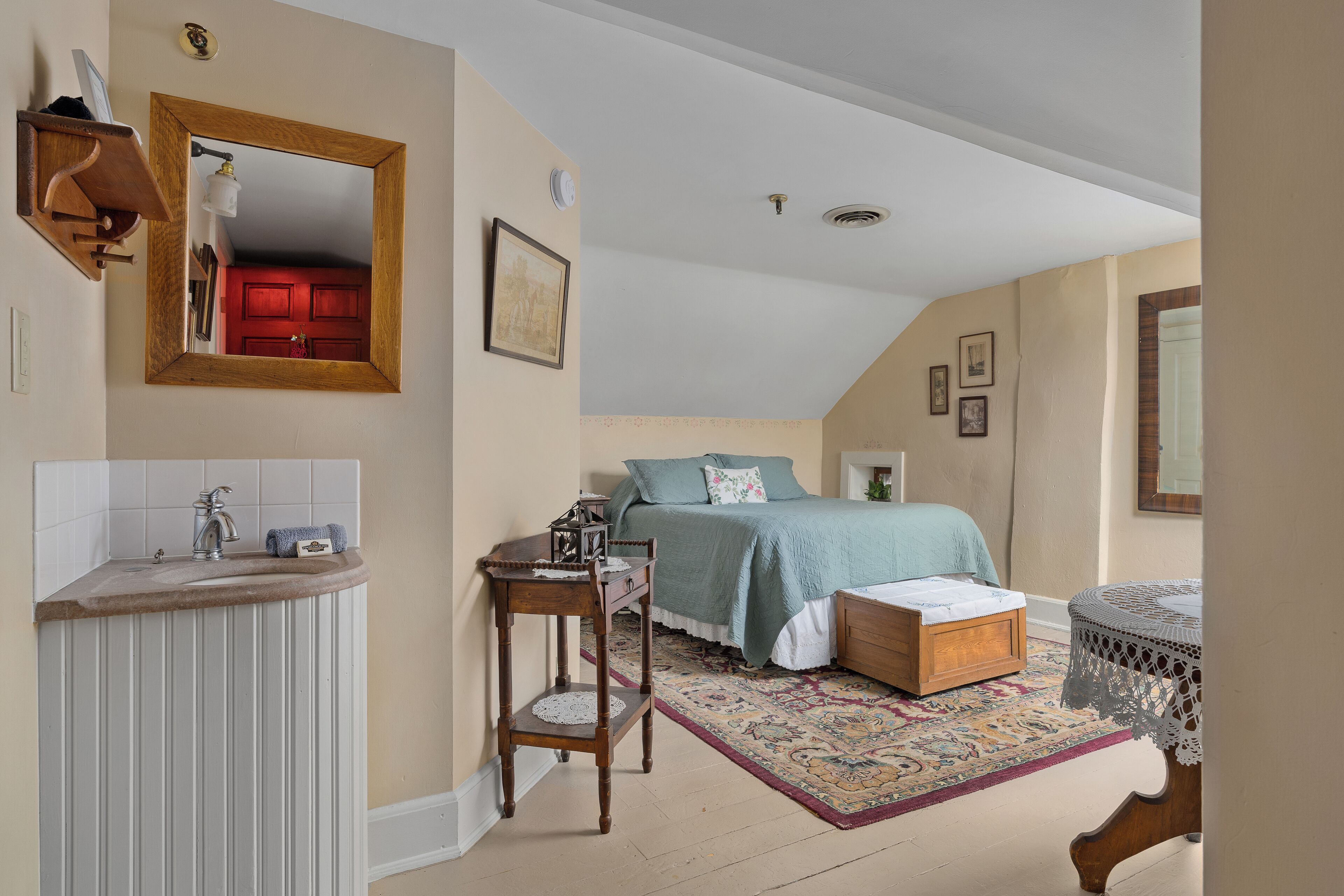 Un dormitorio con cama, mesita de noche y una pequeña mesa con lámpara.
