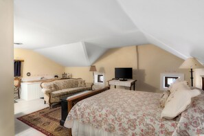 Quarto com cama, sofá, televisão e escrivaninha.