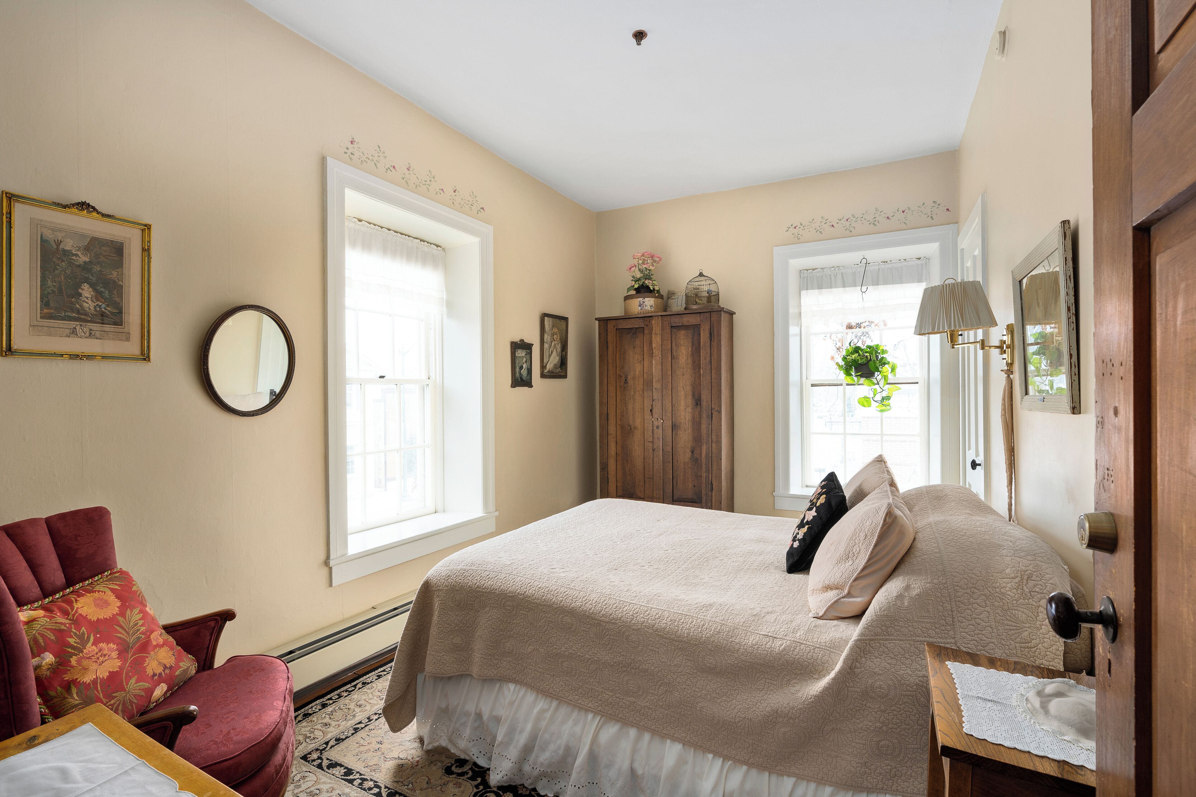 A bedroom with a bed, a chair, a wooden cabinet, and a door.