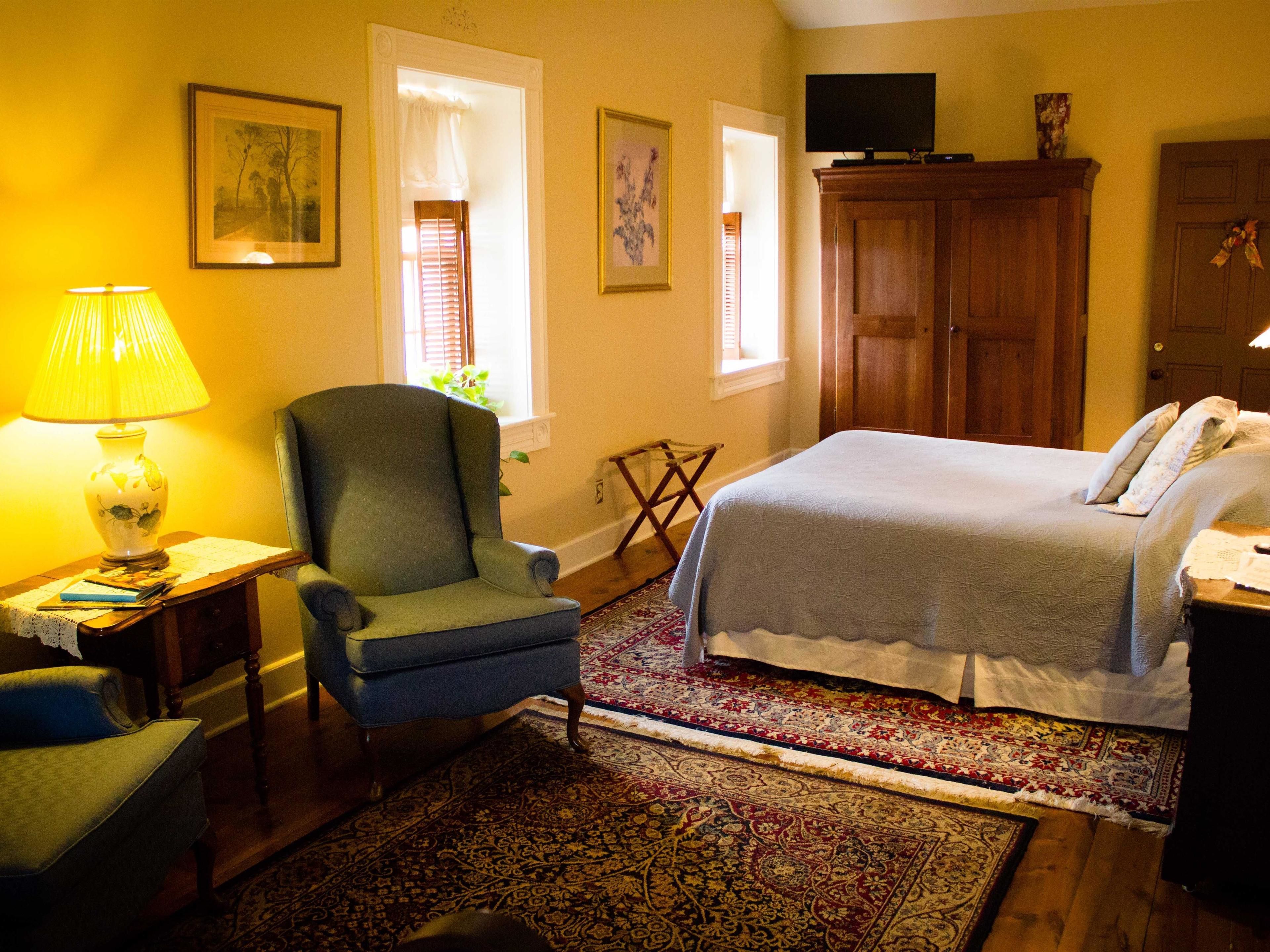 Une chambre à coucher avec un lit, une chaise, une lampe et un téléviseur.