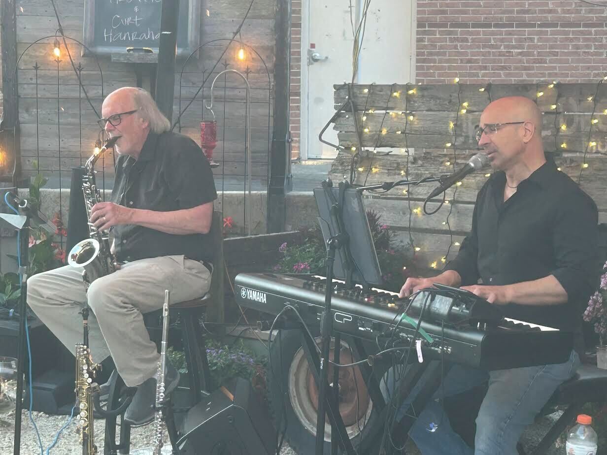 Zwei Musiker treten im Freien mit Musikinstrumenten und einer Yamaha-Tastatur auf.