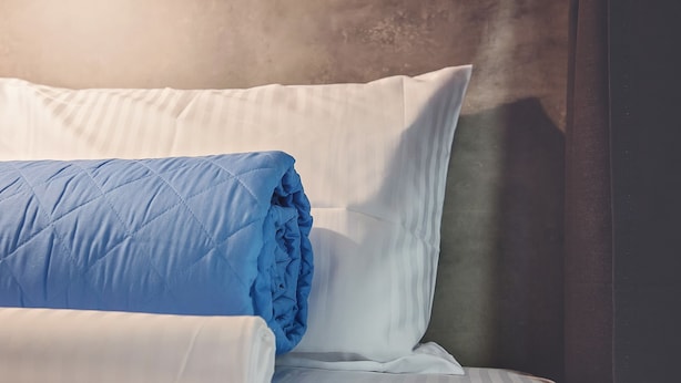 A neatly made bed with a blue quilt and white pillows. - Bedbox Hostel (Athens)