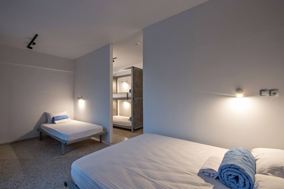 Ein modernes Hotelzimmer mit einem großen Bett, einem kleineren Bett und einer Sitzbank.