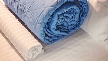 A neatly made bed with a blue blanket and white pillows.