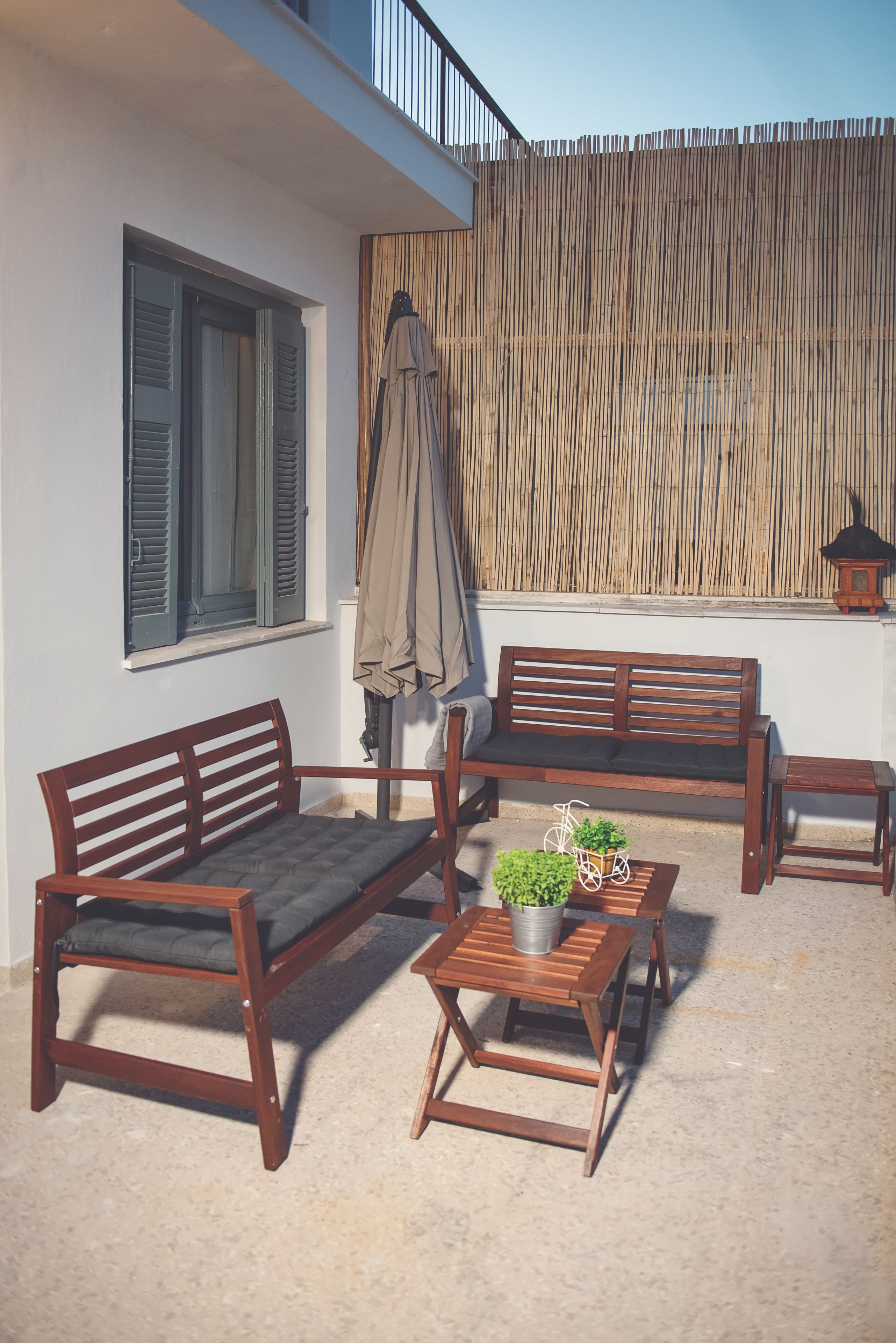 Un área de estar al aire libre con madera, que incluye un sofá, dos sillones y una mesita con una planta en maceta.