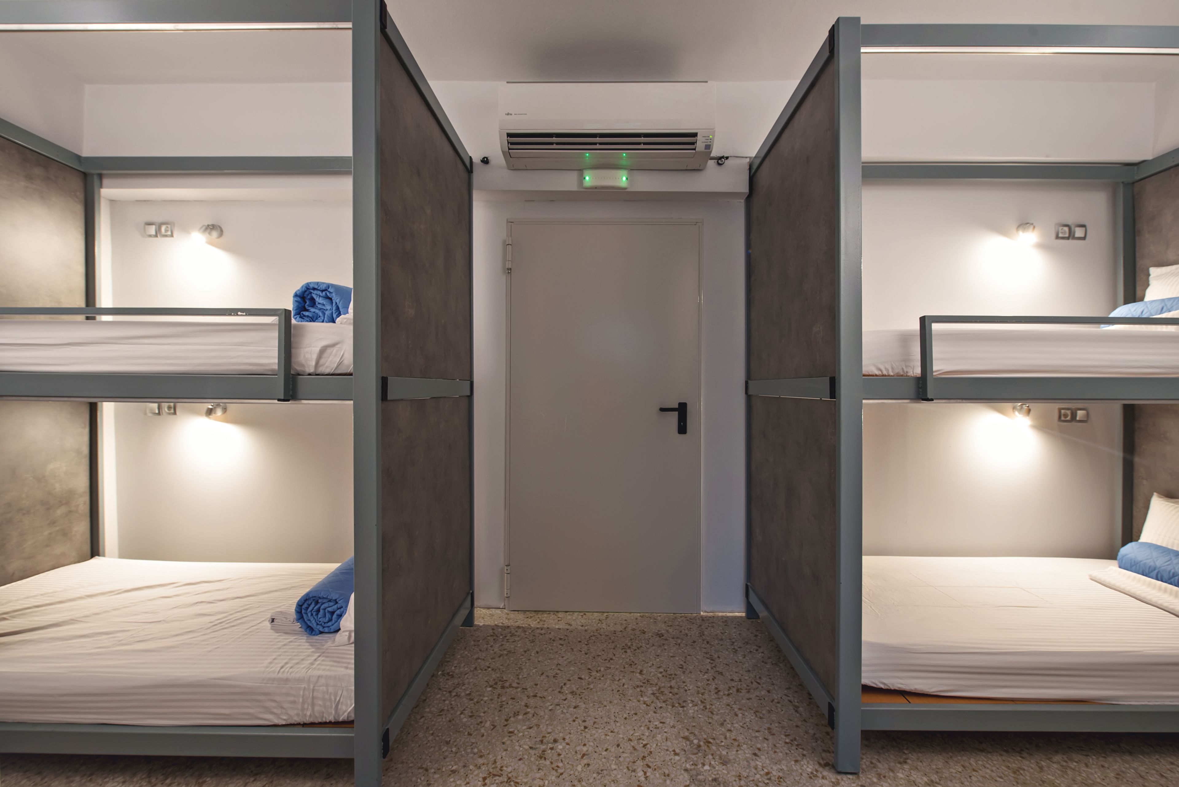 A room with bunk beds, a door, and an air conditioning unit.