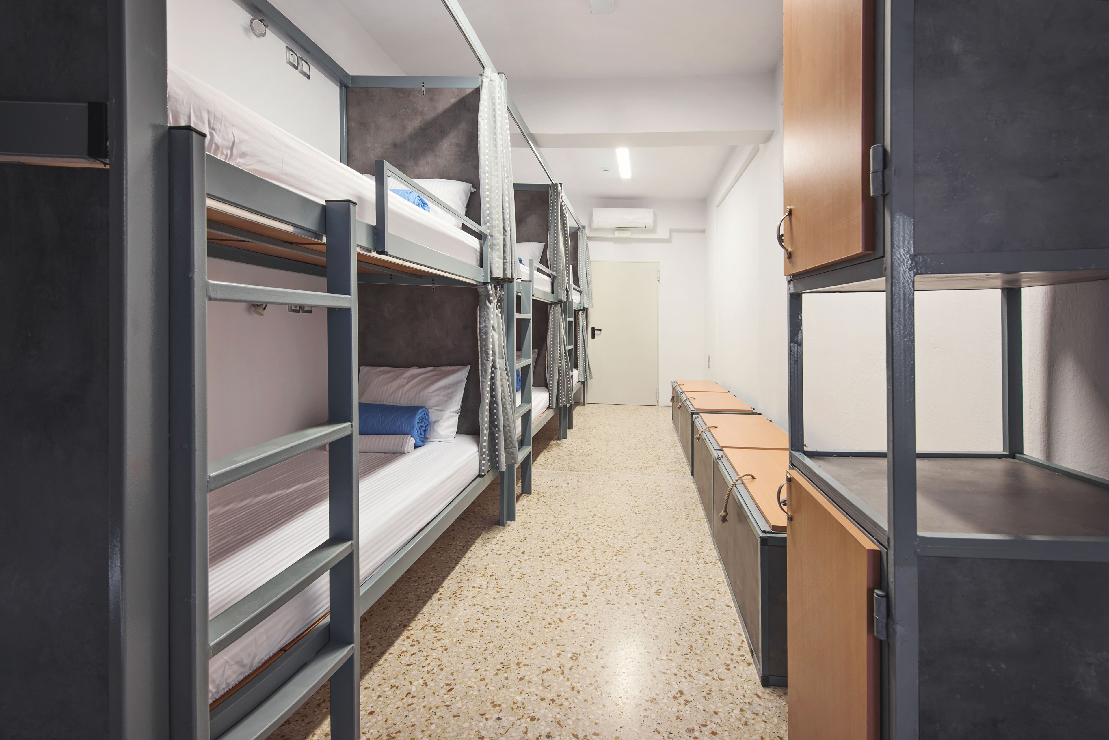 A corridor with bunk beds and storage units, likely in a hostel or dormitory setting.
