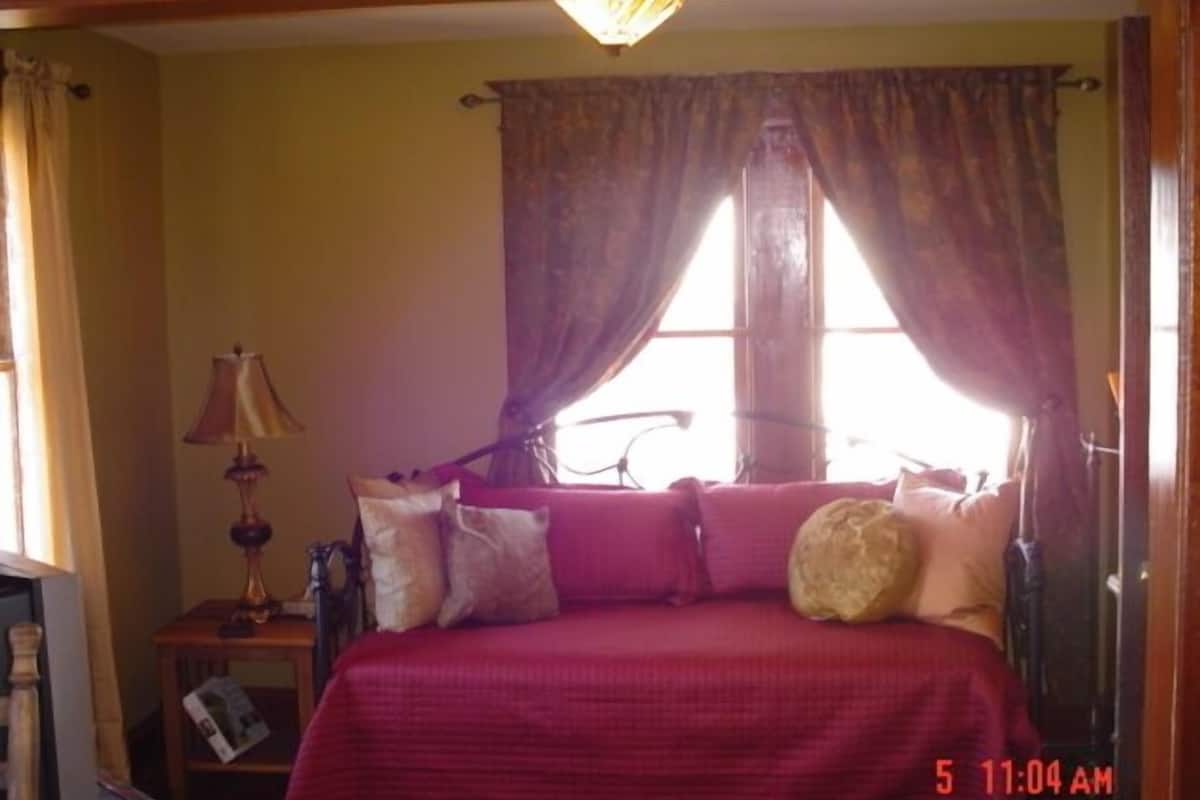 A bedroom with a bed, a nightstand, a lamp, and a window with curtains.