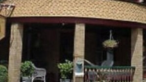 A two-story house with a distinctive corner turret and a wrap-around porch. - The Sea Gypsy (Wildwood)