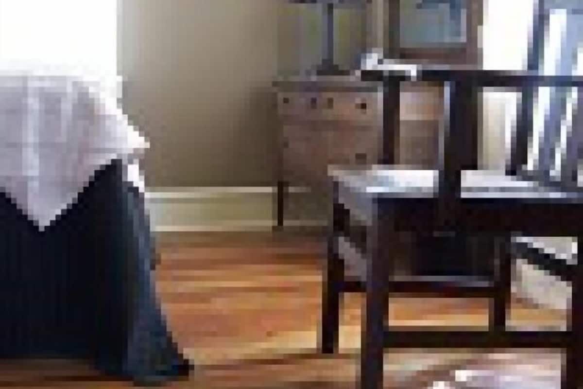 A room with a wooden floor, a chair, a dresser, and a lamp.