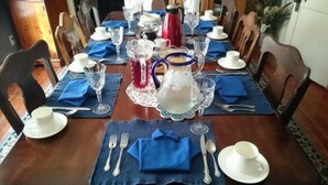 A dining table set with blue placemats, white plates, and silverware. - The Sea Gypsy (Wildwood)