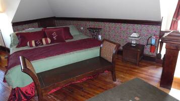 A bedroom with a bed, a wooden chair, a nightstand, and a lamp.