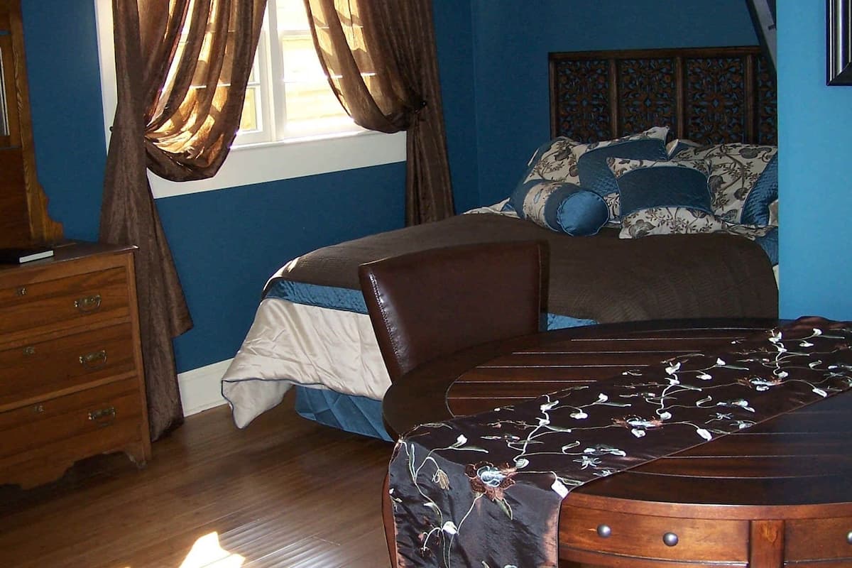 A bedroom with a bed, a dresser, and a chair.