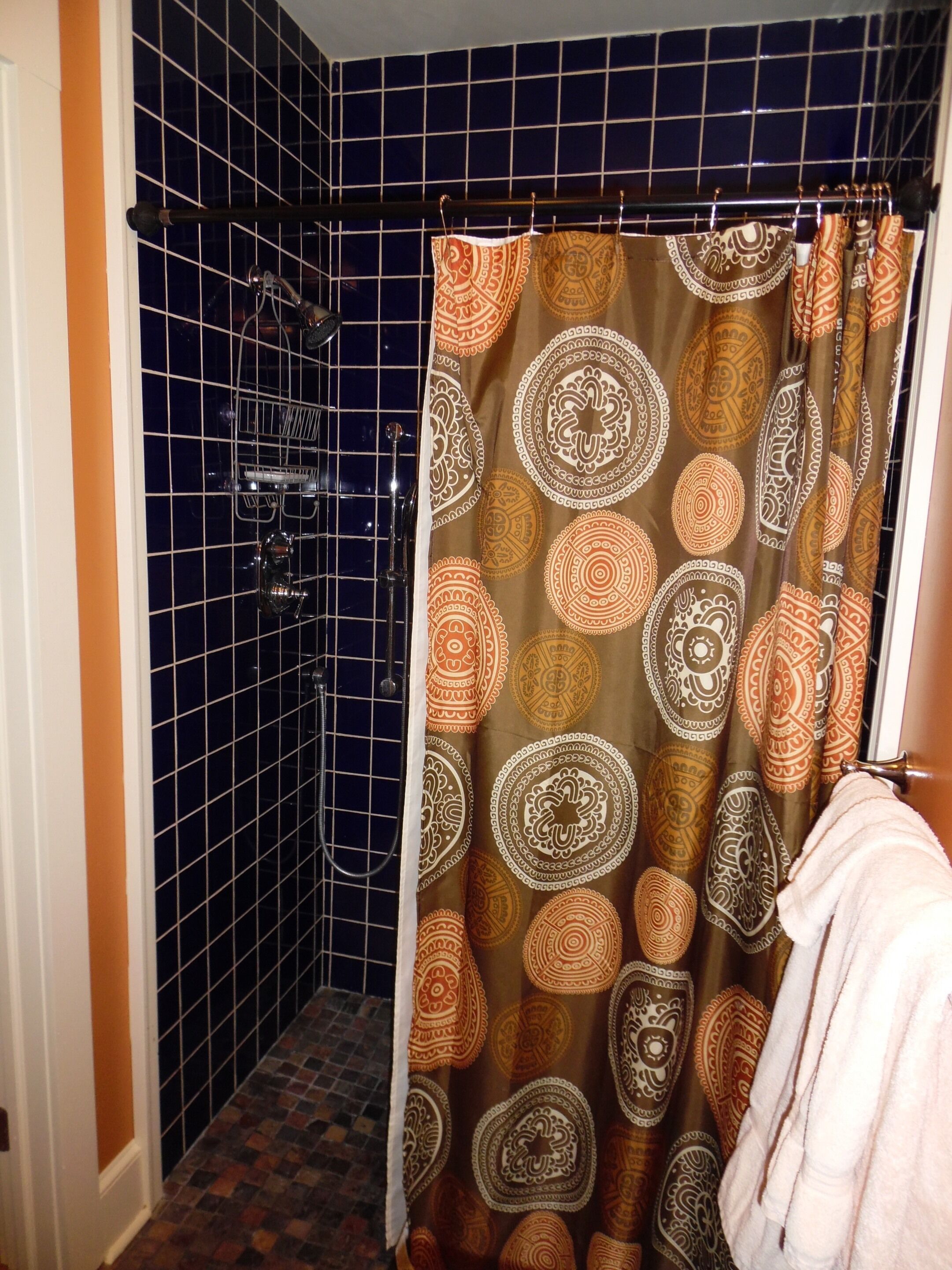 Un bagno con una tenda da doccia decorata con un motivo circolare, pareti piastrellate e un portaserviti.