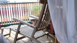 A wooden deck with a single lounge chair and a white curtain. - The Sea Gypsy (Wildwood)