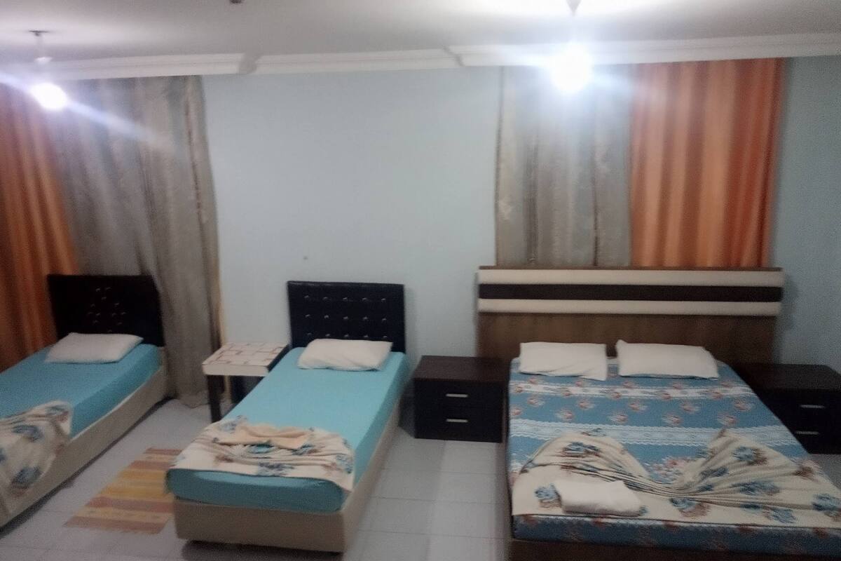 A room with two single beds, a small table, and a nightstand.
