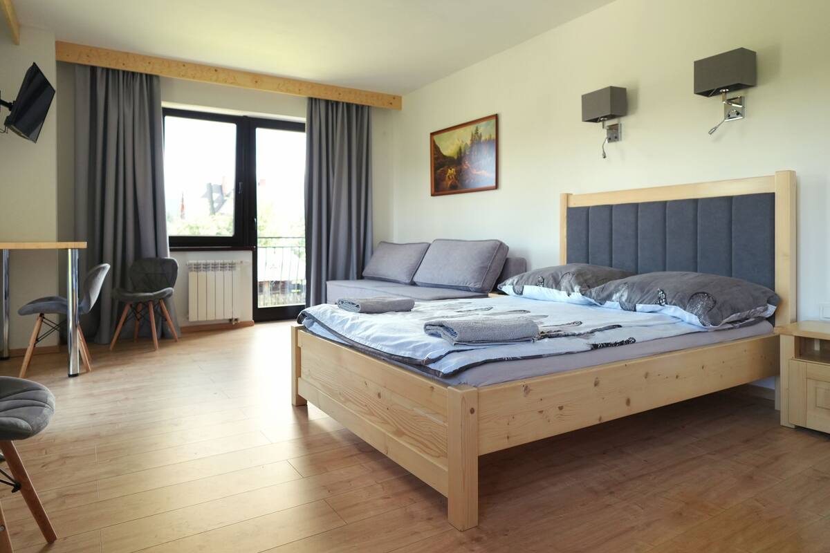 A modern bedroom with a wooden bed, a desk, and a chair.