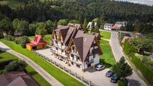 A multi-story building with a sloped roof, surrounded by a well-maintained lawn and a road. - Pod Hawraniem (Bukowina Tatrzanska)