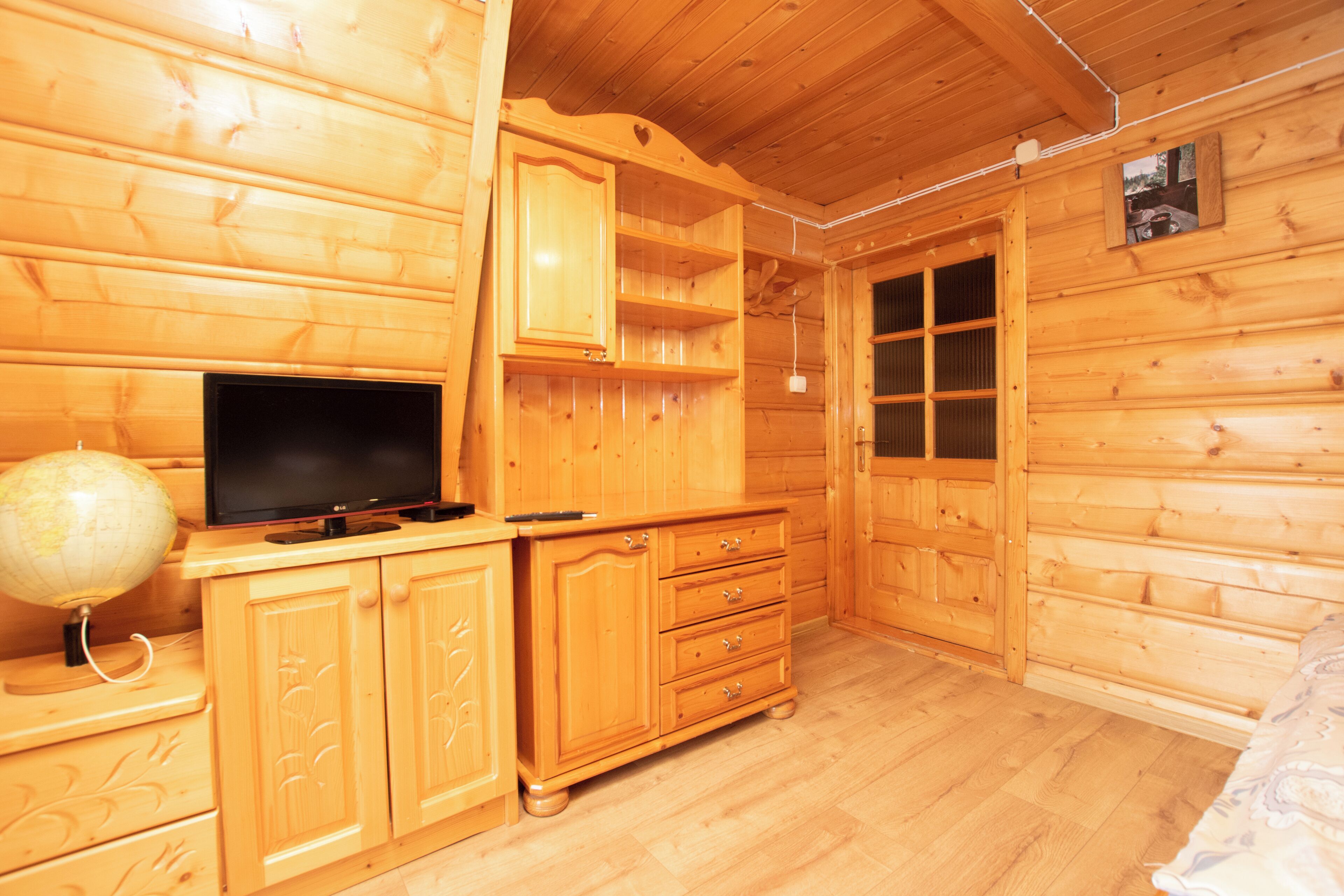 A wooden cabin room with a television on a wooden cabinet, a globe, and a window.