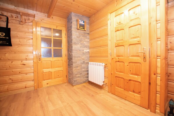 A wooden interior with two doors, a stone pillar, and a white radiator.