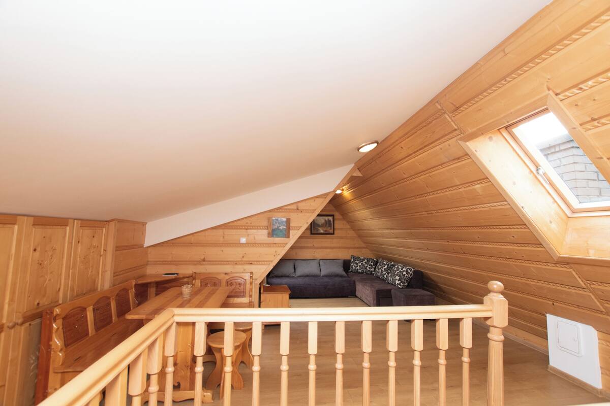 A wooden interior with a loft bedroom, a dining area, and a staircase.