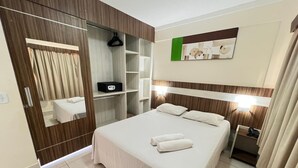 A hotel room with a bed, a bedside table, a mirror, a wardrobe, and a wall-mounted artwork. - Apartment Lacqua DiRoma IV - JC Temporada (Caldas Novas)