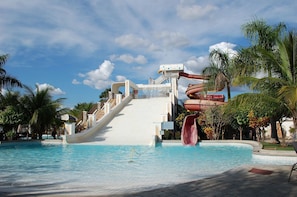 A water park with a large water slide, a pool, and palm trees.