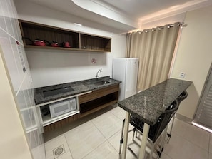 Eine kompakte Küche mit Einbau-Mikrowelle, Spüle und Kühlschrank.
